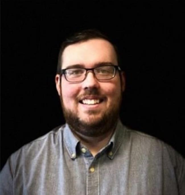 White man with glasses wearing blue button-down